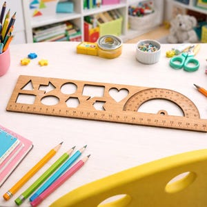 May include: A wooden ruler with shape cutouts and a protractor sits on a white table, surrounded by colorful pencils, notebooks, and other school supplies. A pink cup holds a collection of colored pencils. The scene suggests a creative workspace.