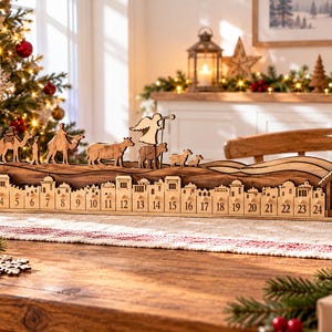 May include: A wooden advent calendar featuring a nativity scene with a town skyline, numbered one through twenty-four. The top layer displays silhouettes of camels, an angel, and livestock, while a stable with a star sits on the far right side.