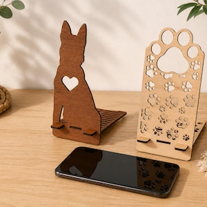 Può includere: Supporti per telefono in legno a forma di cane e impronta di zampa. Il supporto per cani è marrone con un ritaglio a forma di cuore. Il supporto per impronte di zampe è marrone chiaro con ritagli di impronte di zampe.