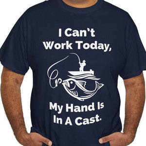May include: A navy blue t-shirt with a white graphic of a fisherman in a boat with a fish on the line. The text on the shirt reads "I Can't Work Today, My Hand Is In A Cast."