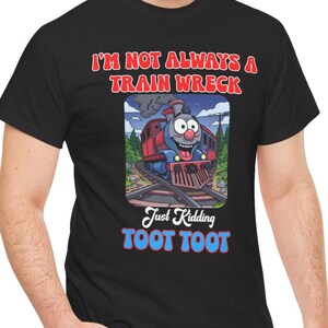 May include: Black t-shirt with a cartoon train graphic. The train is red and blue, with a smiling face. Text on the shirt reads "I'M NOT ALWAYS A TRAIN WRECK" and "Just Kidding TOOT TOOT".