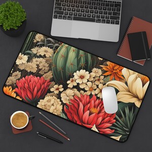May include: A floral and cactus themed mousepad with a white mouse on top. The mousepad features a variety of flowers in shades of red, white, and yellow, as well as a large green cactus.