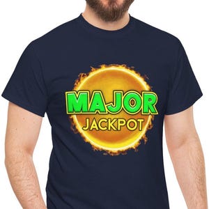 May include: A navy blue short-sleeved t-shirt featuring a central graphic of a glowing yellow sun surrounded by orange flames. The text "MAJOR" is printed in bold green letters with a yellow outline, and "JACKPOT" is in yellow below it.