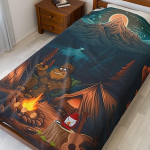 May include: A bedspread featuring a cartoon illustration of a Bigfoot enjoying a campfire in a forest setting. The design includes a tent, guitar, and a mountain landscape with a rising sun. The color palette includes shades of brown, green, and blue.