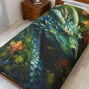 May include: A twin-sized bedspread featuring a detailed illustration of a dragon's head. The dragon is primarily teal and green, with red eyes and white accents. The design includes floral elements in shades of orange and green.
