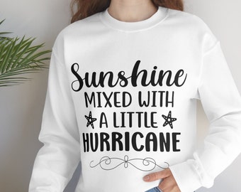 May include: White sweatshirt with black text that reads "Sunshine mixed with a little hurricane" with a starfish on either side of the word "little".