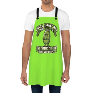 May include: A bright green apron with black straps. The apron features a cartoon pickle with an angry expression and the text "WELL PAINT ME GREEN AND CALL ME A PICKLE" and "I'M DONE DILLIN' WITH YOU PEOPLE".