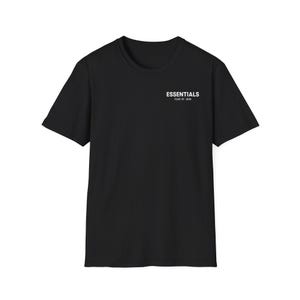 Op de afbeelding: Zwart T-shirt met korte mouwen met het woord "ESSENTIALS" in het wit gedrukt op de linkerbovenborst. Onder het woord "ESSENTIALS" staat de tekst "FEAR OF GOD" in kleinere letters. Het shirt is gemaakt van een zacht materiaal.