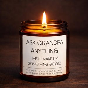 May include: A lit candle in a brown glass jar. The label reads "ASK GRANDPA ANYTHING (HE'LL MAKE UP SOMETHING GOOD)". The candle is made with non-toxic coconut apricot wax and is hand-poured.