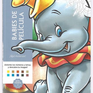 May include: A coloring book featuring Dumbo from the Disney movie. The cover shows a gray elephant with a yellow hat and a red and yellow collar. Text on the cover reads "BABIES DE PELÍCULA" and "¡Qué misterio!" with instructions to color the numbers and letters.