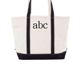 May include: A white canvas tote bag with black handles and trim. The bag has the letters "abc" embroidered on the front in black.