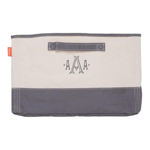 May include: A white canvas storage bin with a gray bottom and a gray handle. The bin has a monogram of "A.A.A." embroidered on the front.