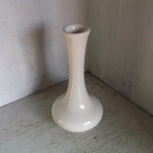 以下が含まれることがあります： 細い首と丸い底を持つ白い陶器の花瓶