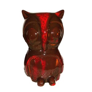 May include: A ceramic owl figurine with a brown and red glaze. The owl has large, round eyes and a detailed beak.