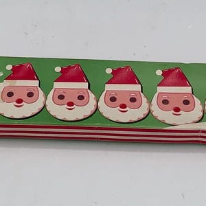 May include: A vintage box of 10 hand-decorated "Soapy Santas" Christmas soaps. Each soap is shaped like Santa Claus's face, with a red hat, white beard, and rosy cheeks. The box has a green background with red and white stripes.