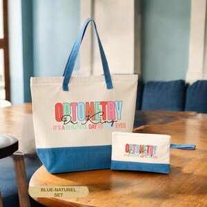 May include: A canvas tote bag and matching pouch set. The tote bag has blue handles and a blue bottom panel. The text "OPTOMETRY Dr. King" is printed on the front, along with the phrase "IT'S A BEAUTIFUL DAY TO EYES". The pouch has a blue handle.