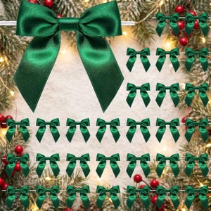 May include: A collection of small, dark green satin ribbon bows arranged in a grid pattern. Each bow features a smooth, shiny texture with two loops and two downward-pointing tails, creating a uniform decorative element for holiday crafts.