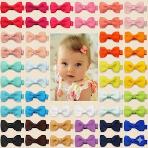 May include: A collection of colorful bow hair clips in various shades of red, pink, orange, yellow, green, blue, brown, purple, and white. A baby girl is in the center of the image, wearing a pink bow clip.