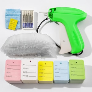 Puede incluir: Una pistola de etiquetas verde y blanca con un cordón negro, una caja de agujas, una bolsa azul con una etiqueta amarilla y montones de etiquetas en blanco de varios colores. Las etiquetas están etiquetadas con "No., STYLE, SIZE, PRICE."