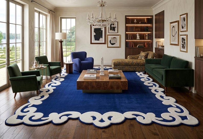 May include: A luxurious living room featuring a large, deep blue rug with a white, ornate border. The room includes green and blue armchairs, a dark green sofa, a wooden coffee table, and a crystal chandelier. Artwork and a patterned chaise lounge add to the elegant decor.