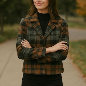 Könnte beinhalten: Ein karierter Blazer in Grün-, Braun- und Grautönen. Die Jacke hat einen klassischen Kragen und einen Knopfverschluss. Die Person trägt einen schwarzen Rollkragenpullover und eine schwarze Hose. Ein stilvoller Mantel.
