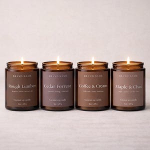 Könnte beinhalten: Vier brennende Kerzen in braunen Gläsern mit den Aufschriften "Rough Lumber", "Cedar Forrest", "Coffee & Cream" und "Maple & Chai". Jede Kerze ist 227 g und als Kokosnuss-Sojawachs gekennzeichnet.