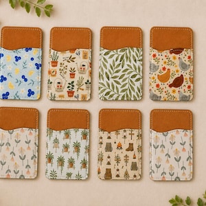 May include: Eight rectangular cardholders with a brown leather top and patterned fabric bottom. Designs include blue floral, potted plants, green leaves, chickens, and other nature-themed patterns. The cardholders are arranged on a light background.