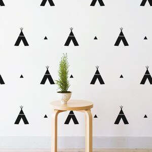 May include: A white wall with a repeating pattern of black teepees and triangles. A small wooden stool with a potted plant sits in front of the wall.