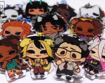 May include: A collection of clear acrylic charms featuring various illustrated chibi-style characters with diverse hair colors, outfits, and expressions. Each charm includes a small metal loop for attachment and a small logo in the corner.