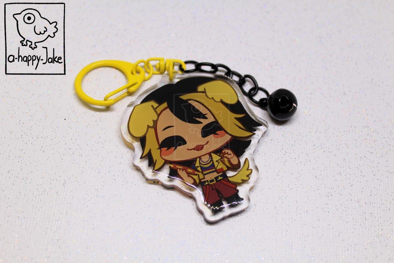May include: An acrylic keychain featuring a cartoon character with yellow dog ears, black hair, and a yellow jacket, attached to a yellow plastic clasp and a black chain with a small black bell. The top left corner displays a bird logo and the text a-happy-Jake.