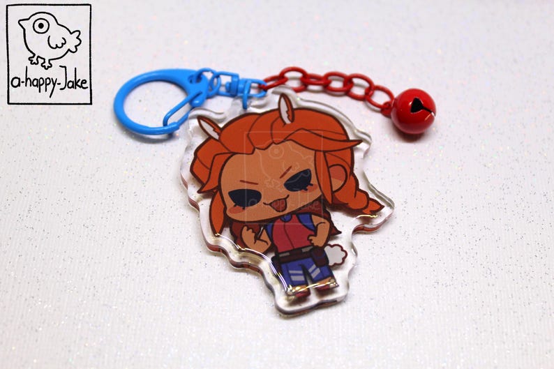 May include: An acrylic keychain featuring a cartoon character with orange hair, a red shirt, and blue pants. The charm is attached to a blue plastic ring and a red chain with a small red bell. The logo a-happy-Jake is visible in the corner.