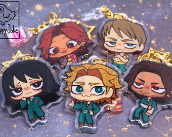 May include: Five acrylic keychains featuring chibi-style characters in green jumpsuits, each with a gold star-shaped clasp. The characters have distinct hair colors and facial expressions. A small logo in the top left corner reads a-happy-jake.