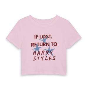 May include: A light pink short-sleeved crop top featuring the dark red text "IF LOST, RETURN TO HARRY STYLES" printed on the front. The design includes three light blue star graphics interspersed between the lines of text on the center chest.