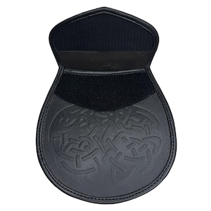 Peut inclure: Sporran en cuir noir avec un motif de n&oelig;ud celtique. Le sporran a une fermeture &agrave; rabat avec une bande Velcro et un dos en tissu noir. Le bas du sporran est arrondi.