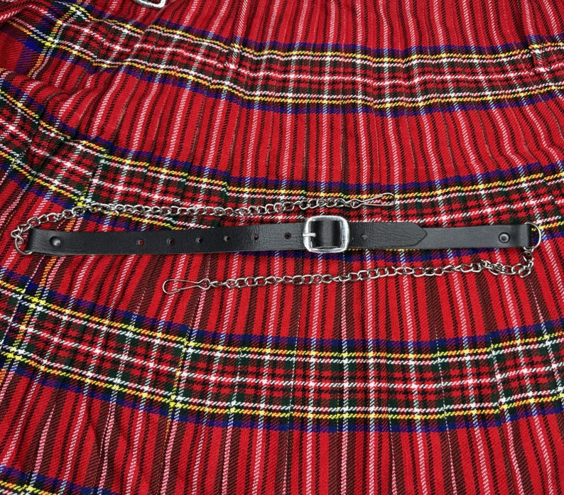 Peut inclure: Un kilt rouge &agrave; carreaux avec une ceinture en cuir noir et une cha&icirc;ne argent&eacute;e. Le kilt pr&eacute;sente un motif tartan traditionnel avec des rayures jaunes, bleues et blanches. La ceinture a une boucle argent&eacute;e et une cha&icirc;ne.