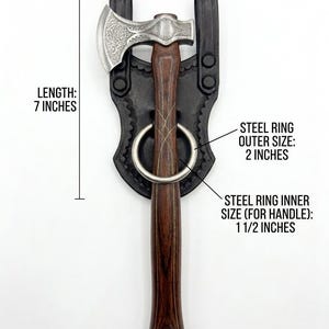 May include: Axe with a wooden handle and a steel head, measuring 7 inches in length and 3.5 inches in width. The axe is held in a black leather sheath with a steel ring. The outer size of the steel ring is 2 inches, and the inner size is 1.5 inches.