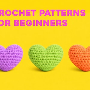 May include: Three crocheted heart shapes in purple, green, and orange sit on a yellow background. The text "CROCHET PATTERNS FOR BEGINNERS" is displayed in pink above the hearts. The hearts are evenly spaced.