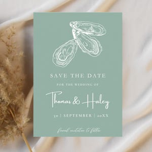 May include: A wedding invitation card in sage green, featuring a white oyster illustration. The text reads "SAVE THE DATE" and the names "Thomas & Haley", with the date "30 | SEPTEMBER | 20XX" and "formal invitation to follow".