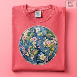 May include: Coral-coloured t-shirt with an embroidered globe design. The globe is decorated with colourful flowers and foliage, with continents in green and blue. The shirt has a crew neck and short sleeves.