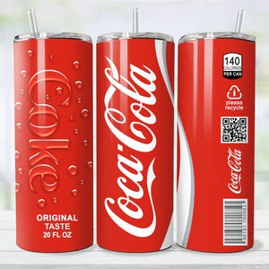 May include: A red 20 fl oz tumbler with a Coca-Cola design. The tumbler features the Coca-Cola logo in white, the word "Coke" in a stylized font, and the text "Original Taste". It also includes a straw and a "please recycle" label.