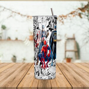 K&ouml;nnte beinhalten: Ein Edelstahlbecher mit einem Comic-Design, das verschiedene Superhelden zeigt, darunter Spider-Man, Captain America und Batman. Der Becher hat einen silbernen Deckel und einen Strohhalm. Der Hintergrund zeigt ein Fenster und einen Holztisch.