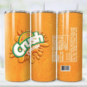 May include: Orange-colored tumbler with the "Crush Orange" logo and a straw. The tumbler has a condensation effect, and the nutrition facts and ingredients are visible on the side. The tumbler is designed to keep drinks cold.