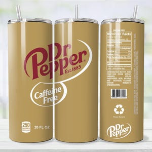 May include: A gold-colored 20 fl oz tumbler featuring the Dr Pepper logo in red and white. The tumbler includes the text "Caffeine Free" and nutritional information. It has a silver lid and a clear straw.