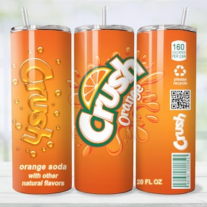 May include: Orange Crush soda tumbler with a straw. The tumbler features the Crush logo and orange slice graphic. The text on the tumbler reads "orange soda with other natural flavors" and "20 FL OZ". The tumbler also includes a recycling symbol and a barcode.