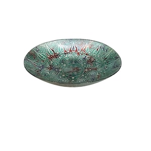 Op de afbeelding: Een decoratieve glazen kom met een gedetailleerd, wervelend patroon in groen, rood en wit. De kom heeft een brede, ondiepe vorm en een getextureerd oppervlak, geschikt om te serveren of tentoon te stellen.