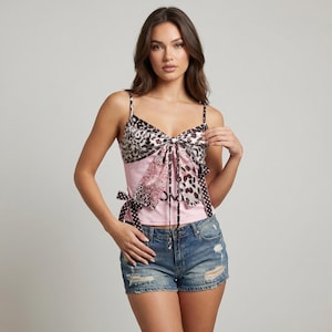 May include: A pink camisole top with a bow detail. The top features a leopard print and polka dot pattern. The straps are thin and the top is paired with denim shorts.