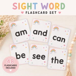Op de afbeelding: Een set van 48 educatieve flashcards met de tekst SIGHT WORD FLASHCARD SET. Elke kaart toont een enkel woord in het zwart, waaronder am, and, can, be, see en the, versierd met kleine kleurrijke regenbogen, sterretjes en hartjes.
