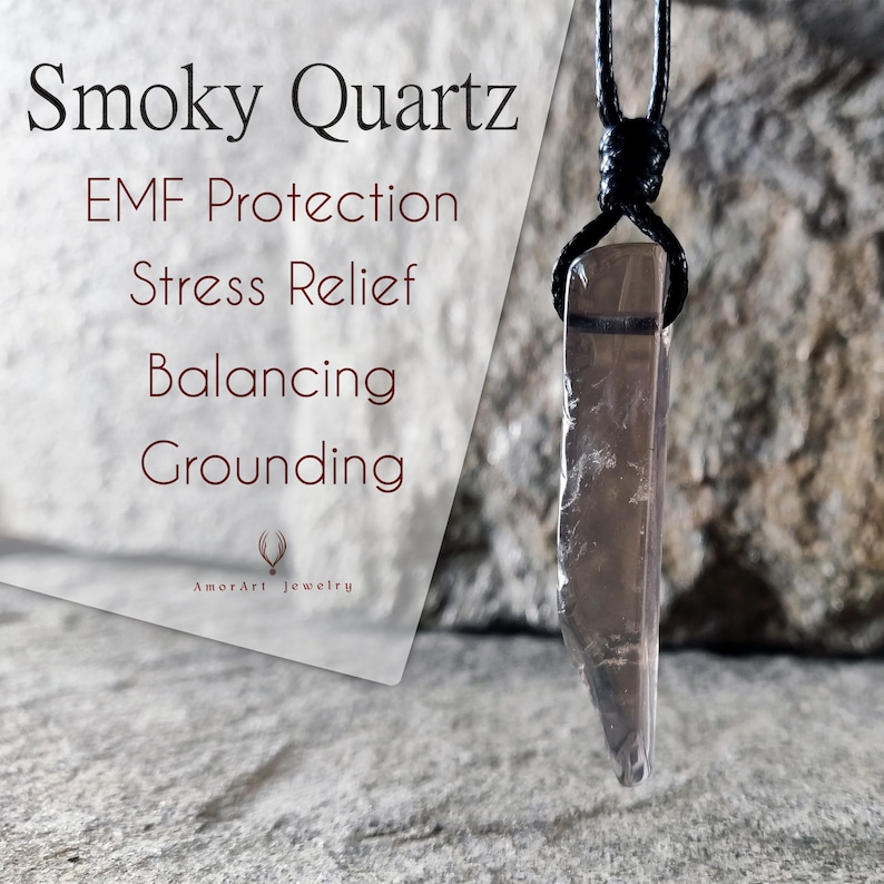 May include: Smoky Quartz pendant necklace with a black cord. The pendant is a translucent, rectangular crystal with a smoky brown hue. Text on the left reads "Smoky Quartz, EMF Protection, Stress Relief, Balancing, Grounding" and "AmorArt Jewelry".