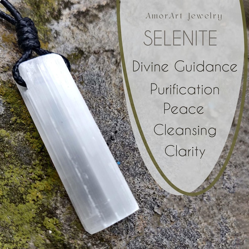 A raw, rectangular selenite pendant hangs from a black cord necklace, positioned on a textured gray stone surface with green and brown moss. To the right, stylized text reads "SELENITE," and lists "Divine Guidance," "Purification," "Peace," "Cleansing," and "Clarity." This selenite necklace is associated with spiritual connection and cleansing.