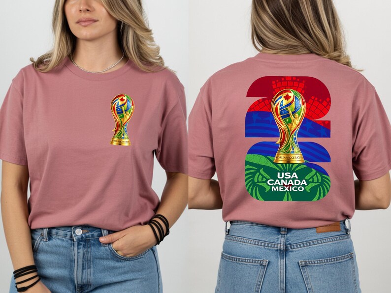 May include: Dusty rose t-shirt featuring a colorful trophy graphic on the front and back. The back design includes the number 26, a trophy, and the text "USA CANADA MEXICO". The shirt is made of a soft material and has short sleeves.